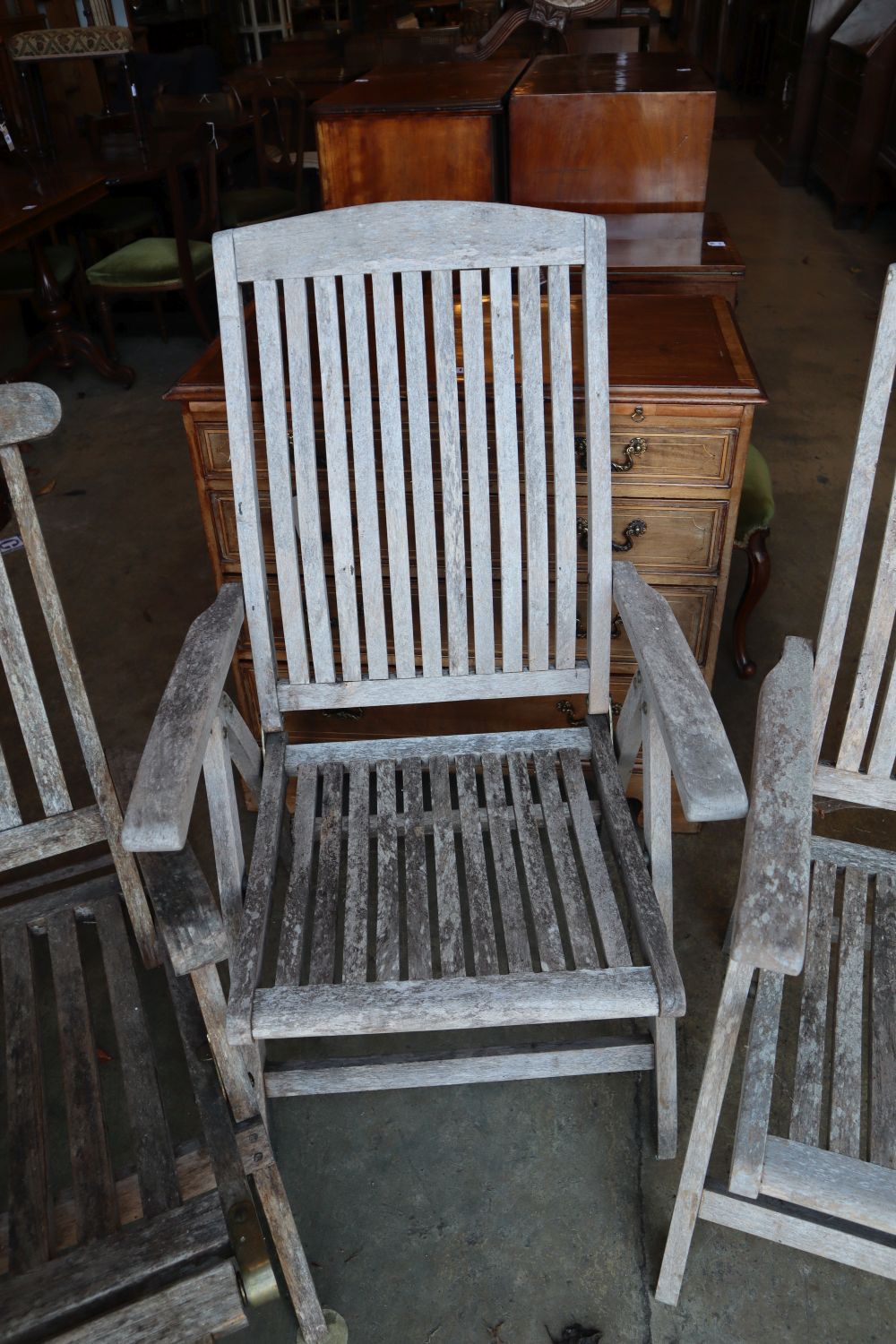 A pair of weathered teak folding garden chairs and a similar steamer chair